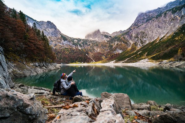 Photo montrant un couple d'explorateurs en randonnée au bord du lac qui montre du doigt la montagne